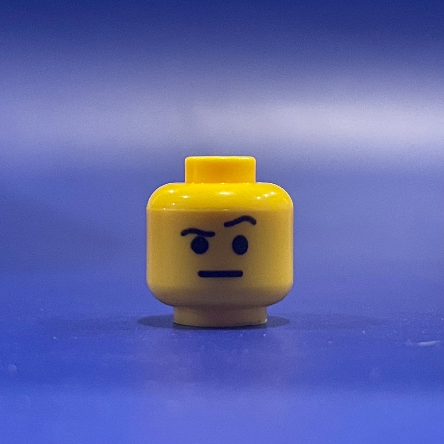 Classic Ayo Head LEGO minifigure yellow head with stern expression on blue background