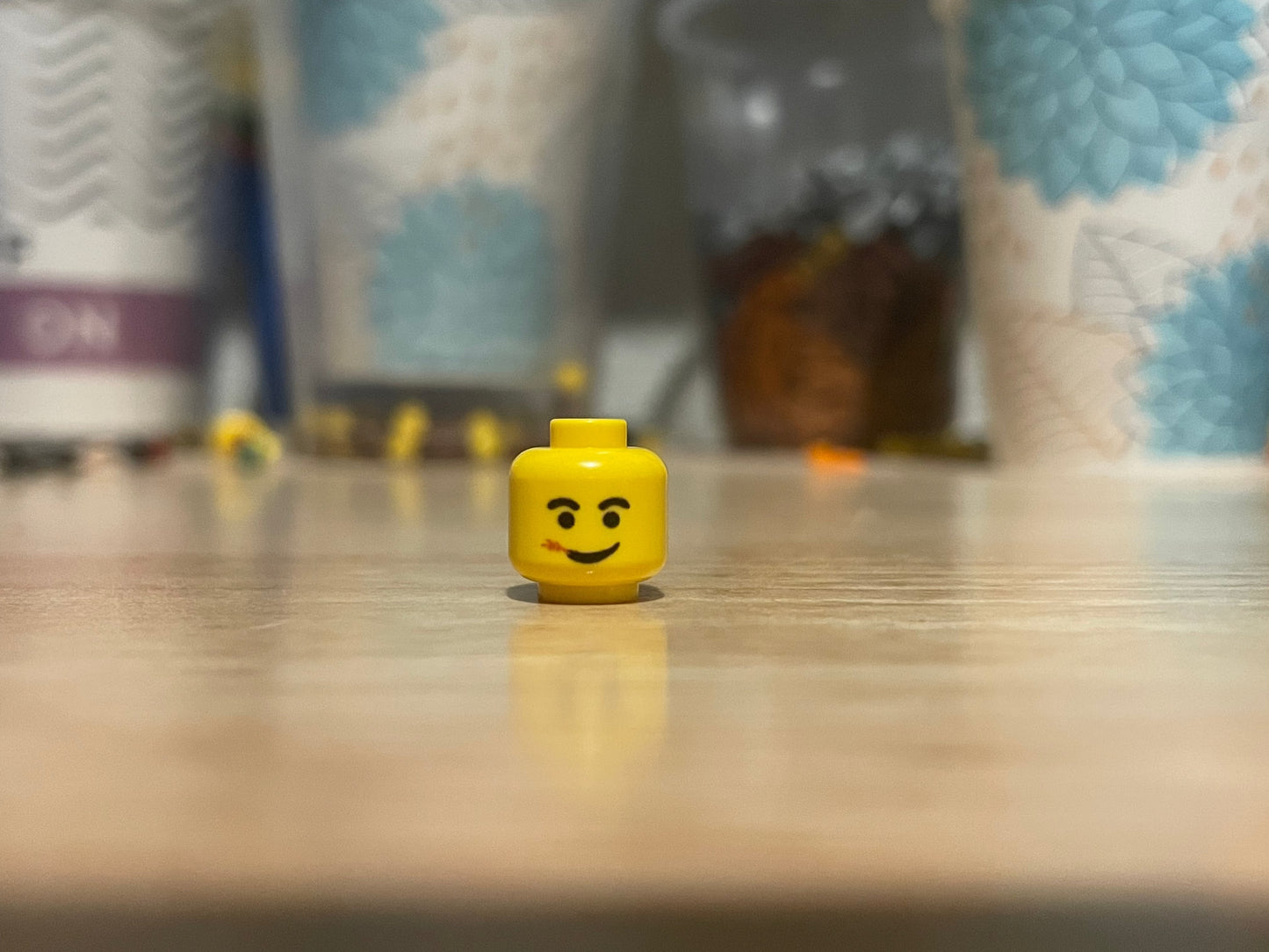 LEGO Straw Chewing Head minifigure piece on table with blurred background