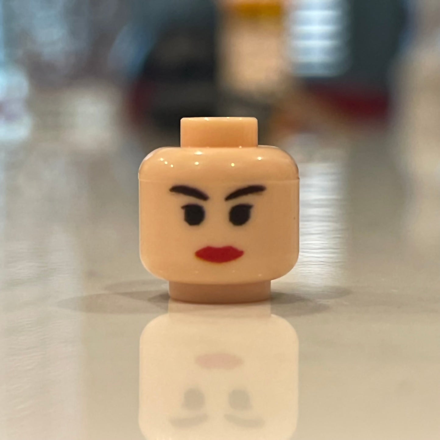 Classic Lover Heads LEGO minifigure head with red lips and arched eyebrows on reflective surface