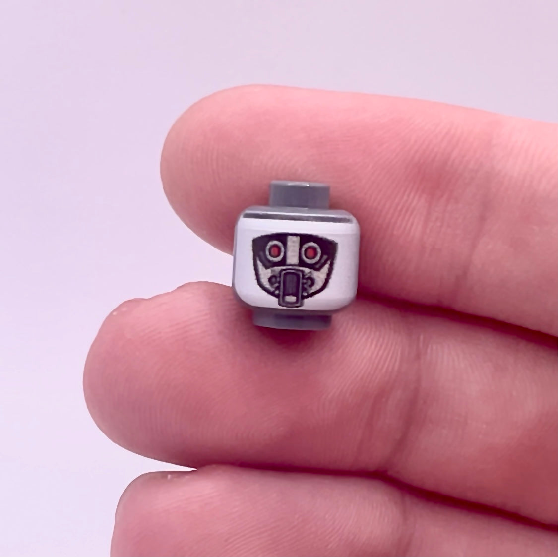 Hand holding a LEGO Classic Robot Guard Head piece with printed robotic face details
