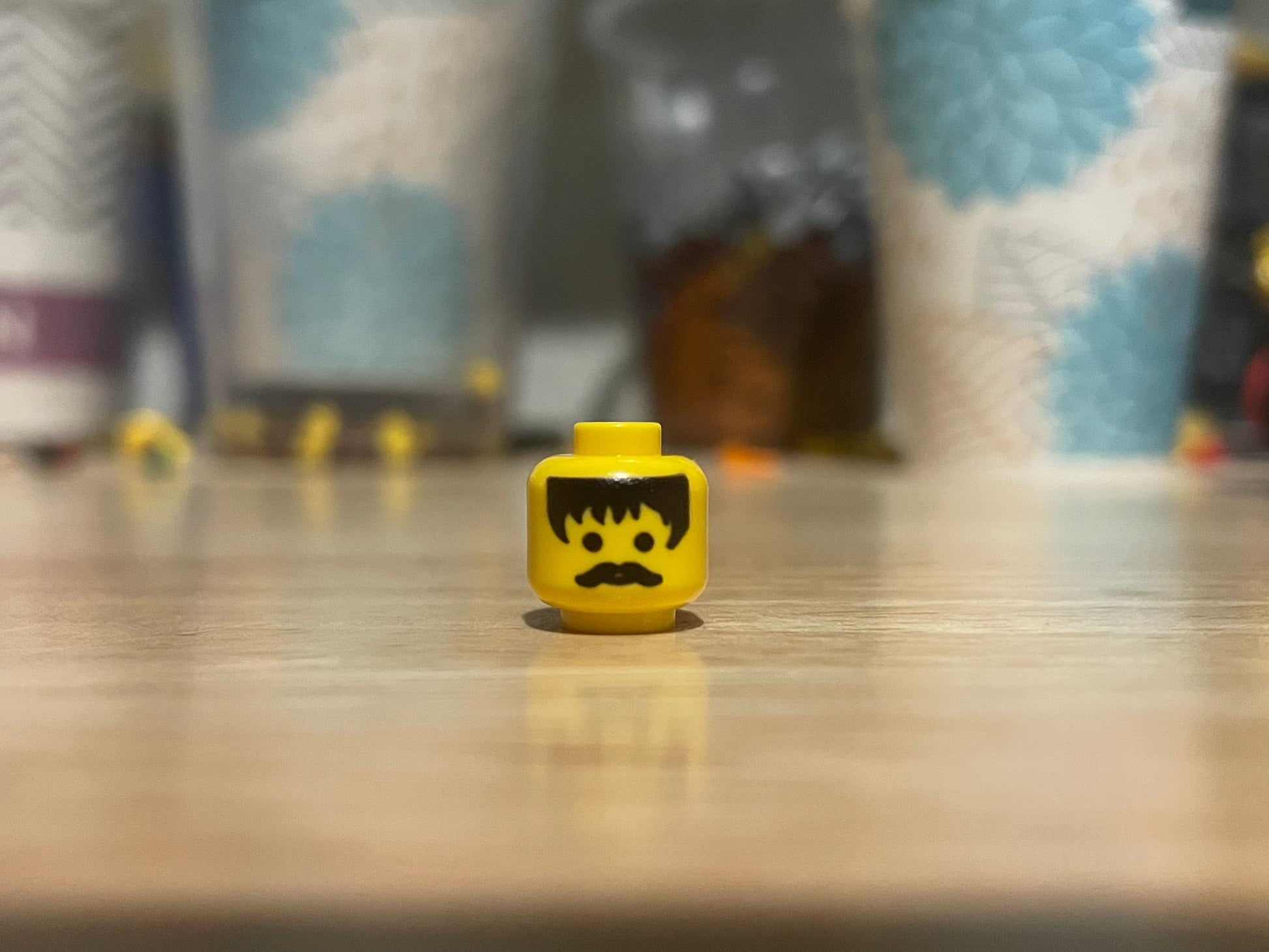 LEGO minifigure black hair head with mustache on wooden surface