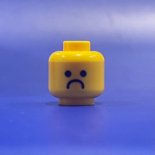 Classic Depressed Head LEGO minifigure part with sad face on blue background