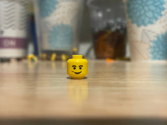 LEGO Straw Chewing Head minifigure piece on table with blurred background
