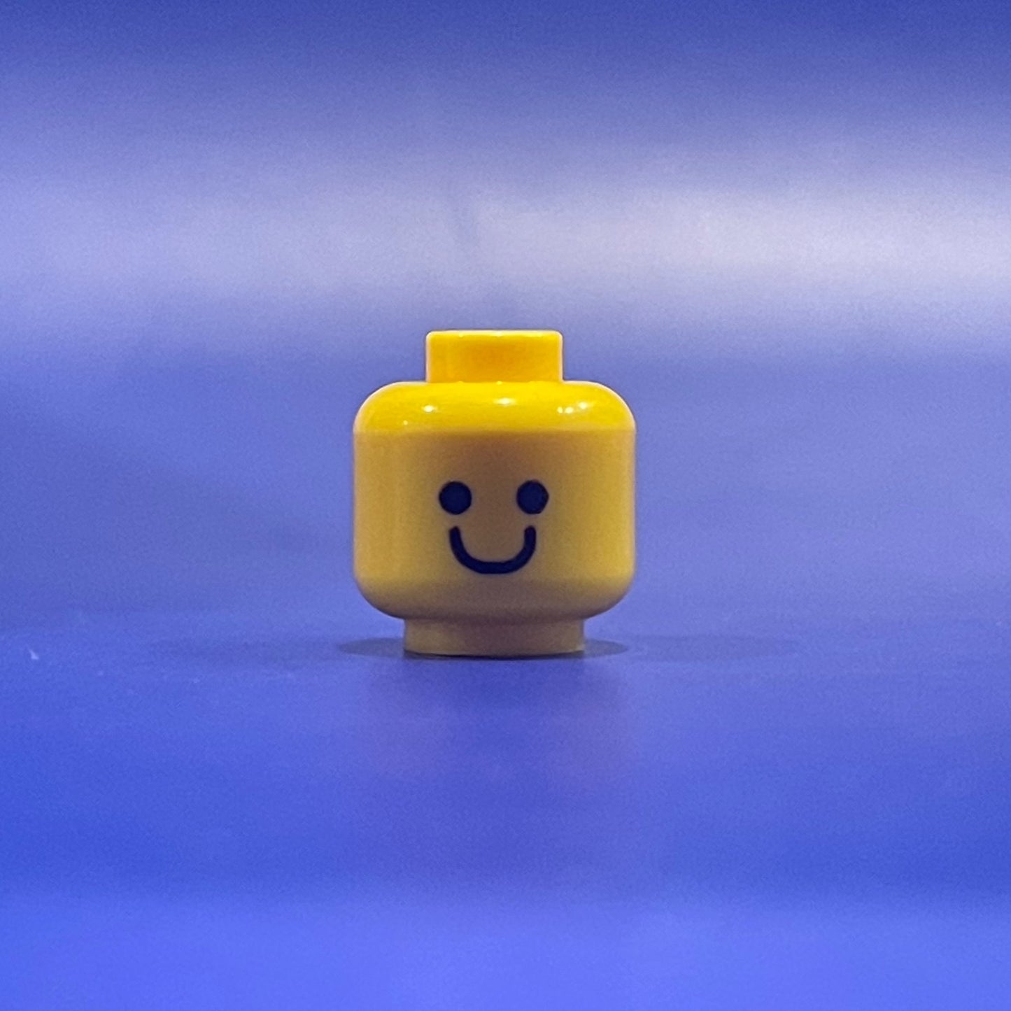 Classic Giddy Head LEGO minifigure yellow head with simple smiling face on blue background