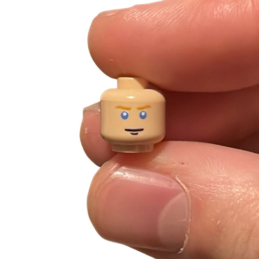 Blue eyed soldier head LEGO minifigure held between fingers
