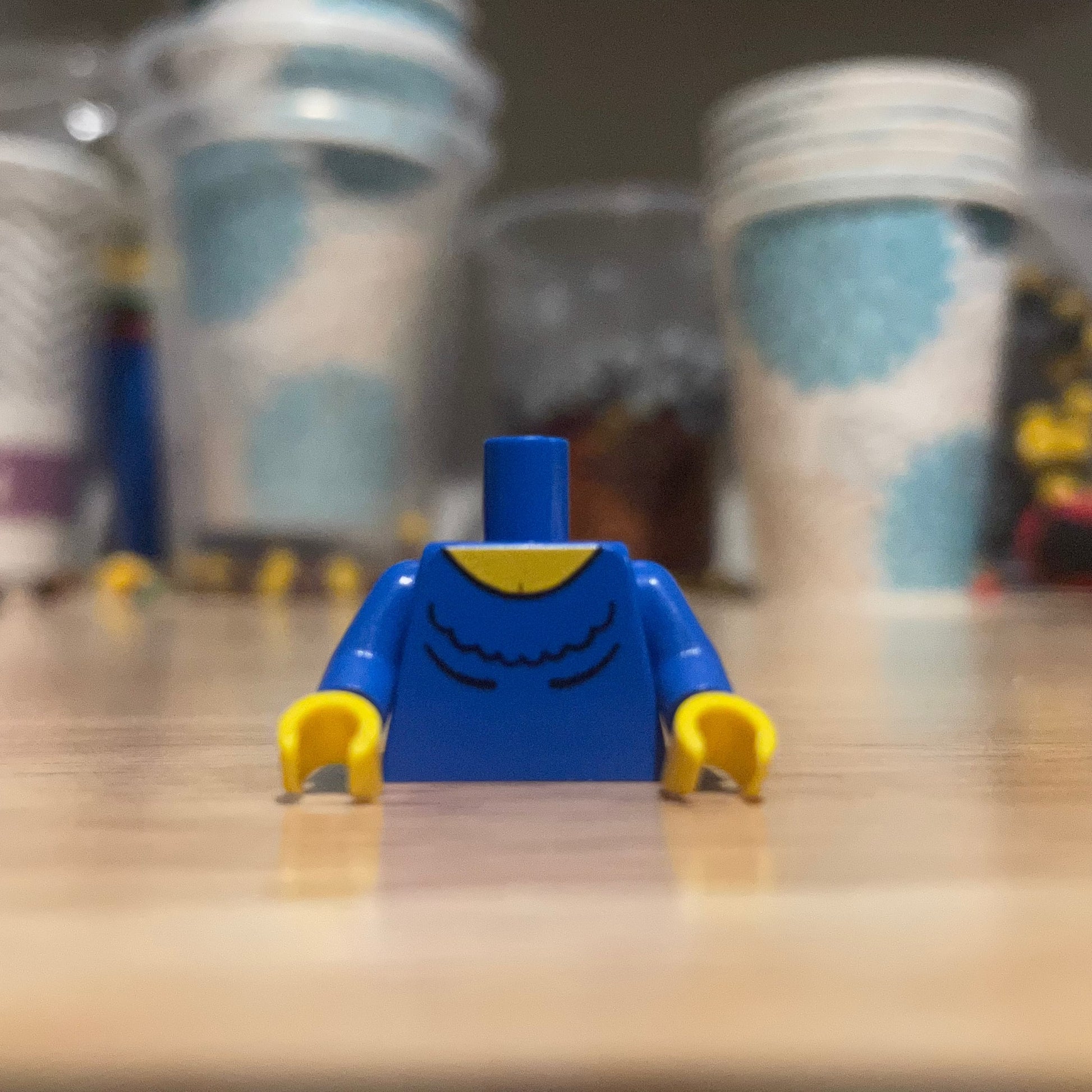 Western Female #2 Torso LEGO minifigure piece with blue shirt and yellow hands on wooden surface