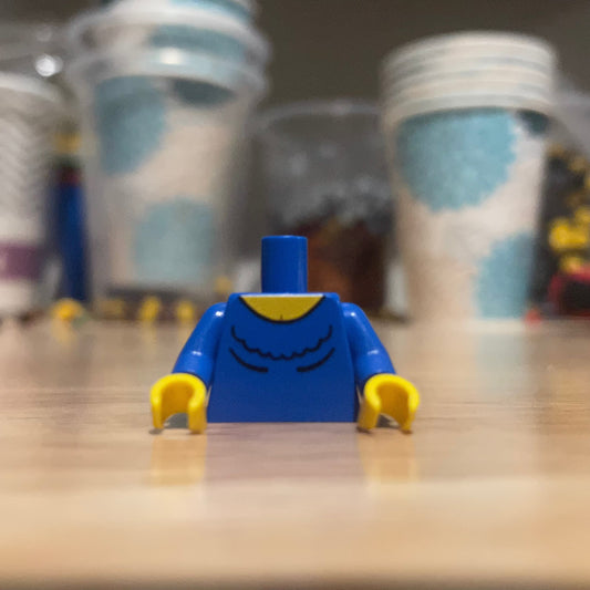 Western Female #2 Torso LEGO minifigure piece with blue shirt and yellow hands on wooden surface