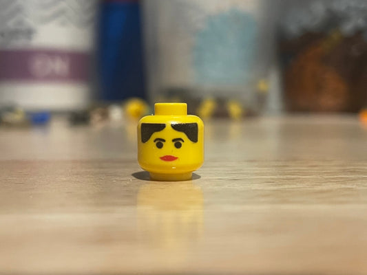 LEGO Western Female minifigure head with black hair and red lips on wooden surface